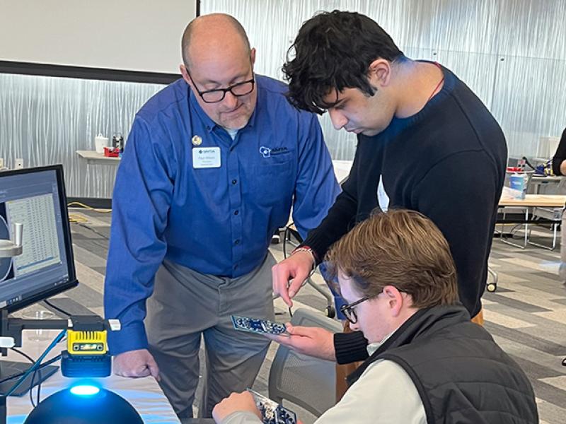 Man helping students with electronics manufacturing